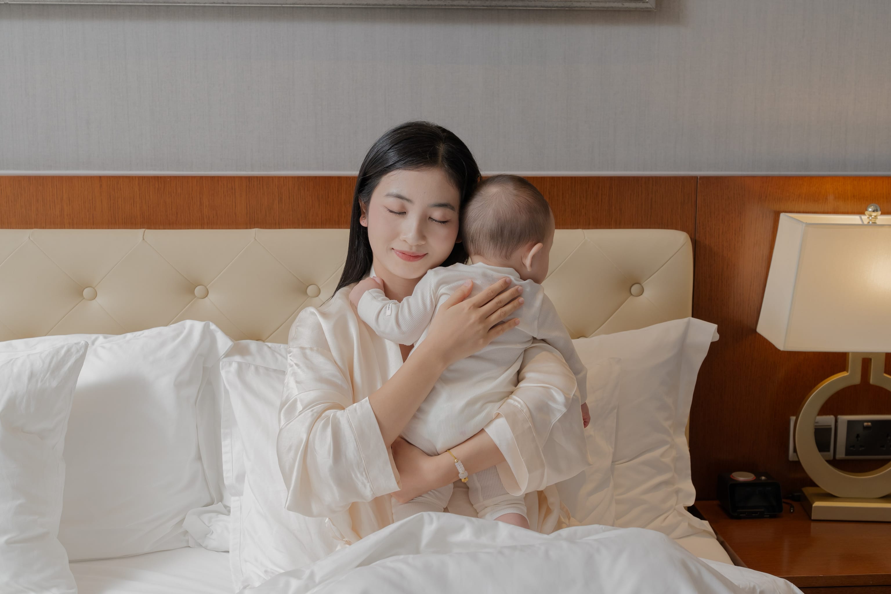 A mother tenderly cradling her swaddled newborn in a quiet suite