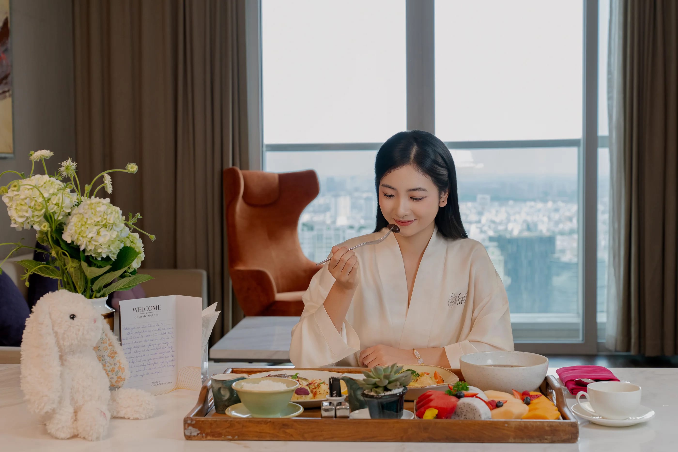 A mother enjoying a recovery breakfast tray by the suite window